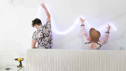 A man and a woman installing a LED neon sign