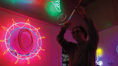 A man hanging a neon sign