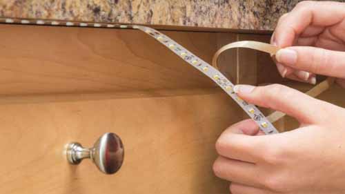 Person installing led strips under a cabinet